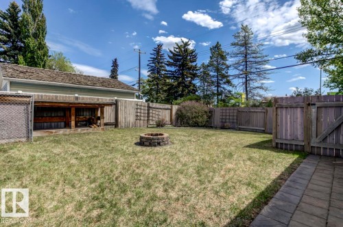 Spacious backyard featuring a block paver fire pit, wood fencing, chain link fencing, a covered storage area, and a paver stone patio - 8511 64 Avenue, Edmonton, AB - Outdoor