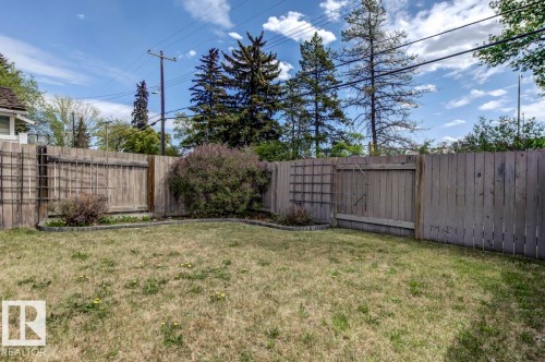 Fenced backyard featuring natural grass, perimeter garden beds, and mature shrubs - 8511 64 Avenue, Edmonton, AB - Outdoor