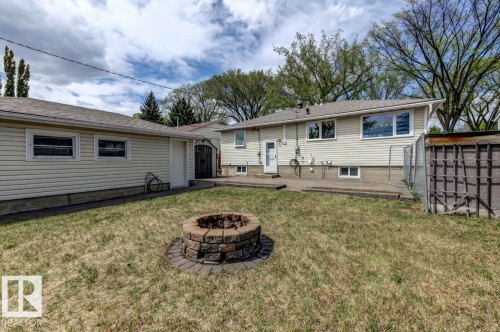 Backyard featuring a stone fire pit, concrete patio, and a detached garage with siding - 8511 64 Avenue, Edmonton, AB - Outdoor