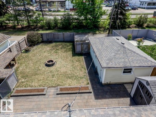 Expansive backyard featuring a central fire pit, natural grass lawn, and a wooden privacy fence - 8511 64 Avenue, Edmonton, AB - Outdoor With Deck Patio Veranda