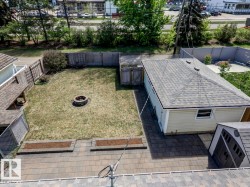 Expansive backyard featuring a central fire pit, natural grass lawn, and a wooden privacy fence - 