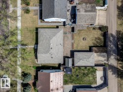 Overhead property view featuring a shingled roof, a detached garage, a fire pit area, and a concrete driveway - 