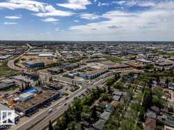 Aerial perspective of a mixed-use district featuring commercial buildings, residential properties, and paved roadways - 