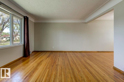 Spacious interior room featuring wood flooring, a multi-pane window, neutral wall paint, and white crown molding - 8511 64 Avenue, Edmonton, AB - Indoor Photo Showing Other Room