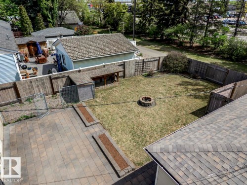 Expansive rear yard featuring a paved patio, grassy area, and a built-in fire pit - 8511 64 Avenue, Edmonton, AB - Outdoor With Deck Patio Veranda