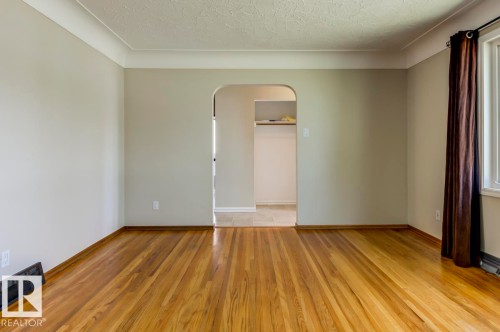 Spacious room featuring wood-finish flooring, light-toned walls, and crown molding - 8511 64 Avenue, Edmonton, AB - Indoor Photo Showing Other Room