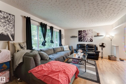Spacious living area featuring light wood-finish flooring, white walls, and a large window with ample natural light - 13211 77 Street Nw, Edmonton, AB - Indoor Photo Showing Living Room