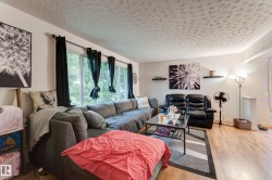 Spacious living area featuring light wood-finish flooring, white walls, and a large window with ample natural light - 