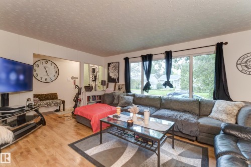 Living area featuring wood-finish flooring, a large picture window, and a light-colored ceiling - 13211 77 Street Nw, Edmonton, AB - Indoor Photo Showing Living Room