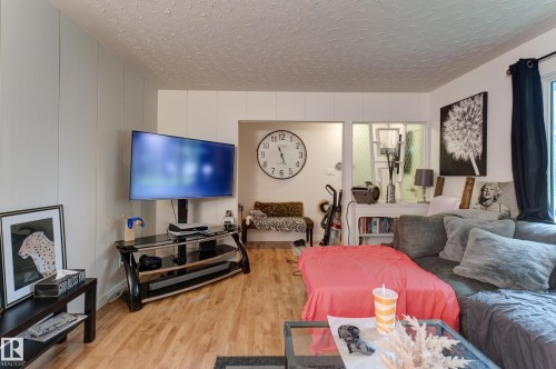 Living area featuring wood-finish flooring, white paneled walls, and a recessed doorway - 13211 77 Street Nw, Edmonton, AB - Indoor Photo Showing Living Room