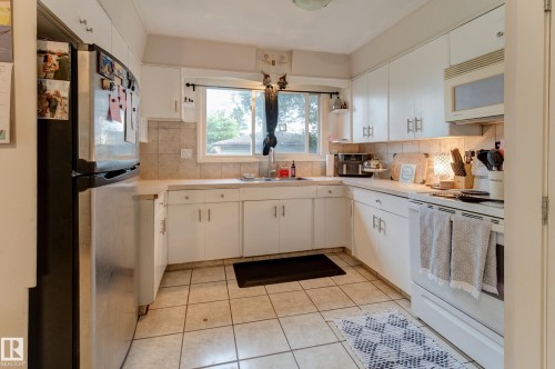 Kitchen featuring white cabinetry, a neutral tiled backsplash, and light-toned countertops - 13211 77 Street Nw, Edmonton, AB - Indoor Photo Showing Kitchen With Double Sink