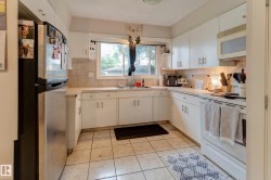 Kitchen featuring white cabinetry, a neutral tiled backsplash, and light-toned countertops - 
