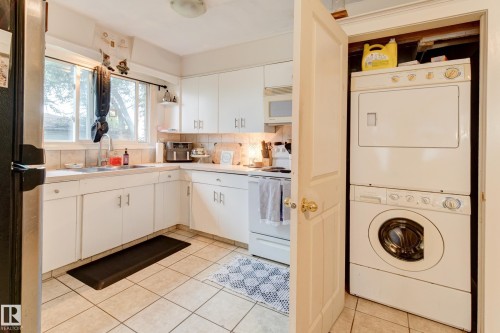 Kitchen featuring white cabinetry, tile countertops, a tile backsplash, and tile flooring - 13211 77 Street Nw, Edmonton, AB - Indoor Photo Showing Laundry Room