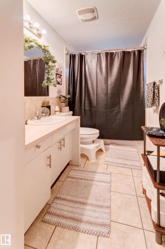 White vanity with chrome hardware, an integrated sink, and a mirrored medicine cabinet - 13211 77 Street Nw, Edmonton, AB - Indoor Photo Showing Bathroom