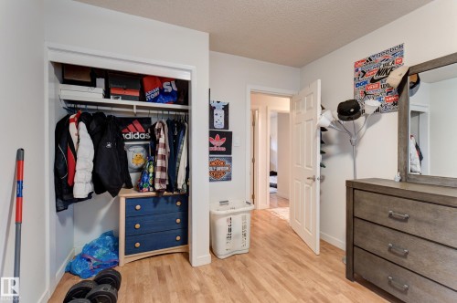 Recessed closet with integrated shelving and clothing rod, wood-finish flooring, white walls, and a white interior door with a silver-tone handle - 13211 77 Street Nw, Edmonton, AB - Indoor Photo Showing Other Room