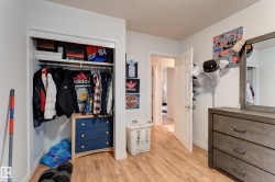 Recessed closet with integrated shelving and clothing rod, wood-finish flooring, white walls, and a white interior door with a silver-tone handle - 