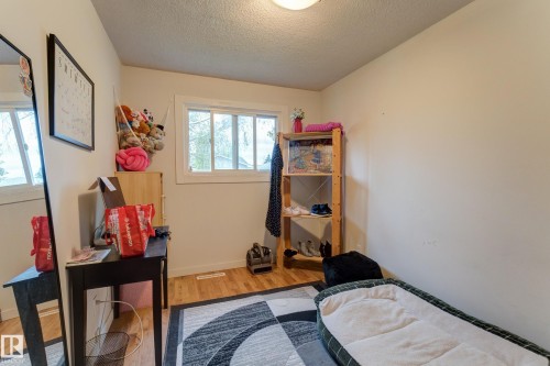 Bright room featuring a window with white trim, wood-finish flooring, and light-colored walls - 13211 77 Street Nw, Edmonton, AB - Indoor Photo Showing Bedroom