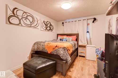 Bedroom featuring wood-finish flooring, a window with curtains, and a ceiling-mounted light fixture - 13211 77 Street Nw, Edmonton, AB - Indoor Photo Showing Bedroom