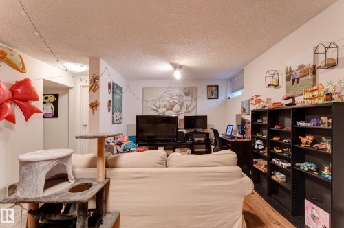 Interior space featuring white walls, wood-finish flooring, a built-in shelving unit, a window, and overhead lighting - 13211 77 Street Nw, Edmonton, AB - Indoor Photo Showing Living Room