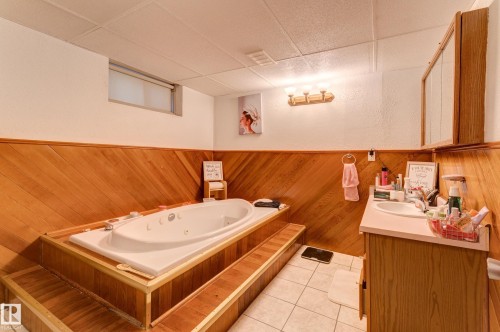 Built-in jetted tub with wood-finish surround, wood-paneled walls, and tiled flooring - 13211 77 Street Nw, Edmonton, AB - Indoor Photo Showing Bathroom
