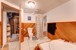 Bathroom featuring wood-paneled walls, white wall paint, and a drop ceiling - 
