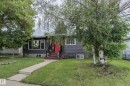 Grey siding exterior with a bright red entry door and white trim windows - 13211 77 Street Nw, Edmonton, AB  - Outdoor With Facade 