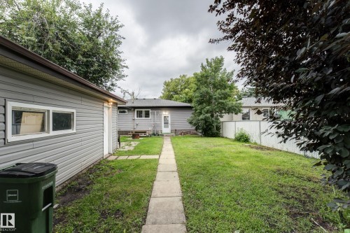 Expansive backyard featuring a concrete pathway, a detached garage with horizontal siding, and a rear entrance to the main residence - 13211 77 Street Nw, Edmonton, AB - Outdoor