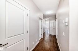 Hallway featuring dark wood-finish flooring, light grey painted walls, white trim, and recessed lighting - 