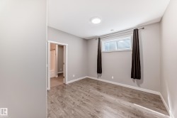 Neutral-toned room featuring wood-finish flooring, a contemporary ceiling light, and a window with blinds - 
