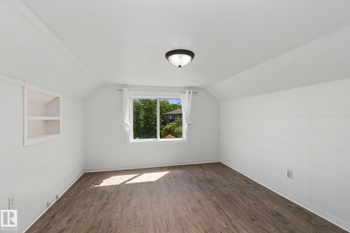 Spacious room featuring wood-finish flooring, a white-framed window, and a built-in recessed shelf - 11147 78 Avenue Nw, Edmonton, AB 