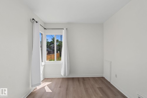 Bright interior space with a bay window, wood-finish flooring, white walls, and white baseboards - 11147 78 Avenue Nw, Edmonton, AB 