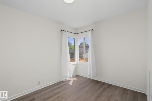 Corner window configuration with white trim, light neutral wall paint, and wood-finish flooring - 11147 78 Avenue Nw, Edmonton, AB 