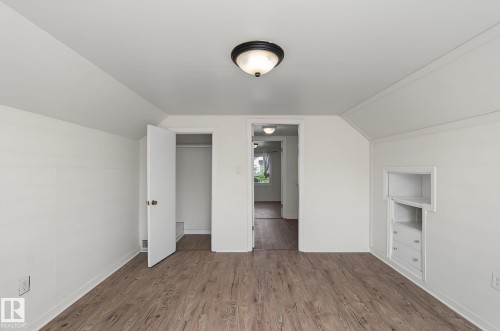Room featuring wood-finish flooring, white painted walls, and an overhead flush-mount light fixture - 11147 78 Avenue Nw, Edmonton, AB 