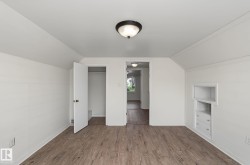 Room featuring wood-finish flooring, white painted walls, and an overhead flush-mount light fixture - 