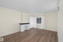Spacious room featuring wood-finish flooring, a decorative fireplace with a dark mantel, and ample natural light from a large window - 11147 78 Avenue Nw, Edmonton, AB  - Indoor Photo Showing Other Room 