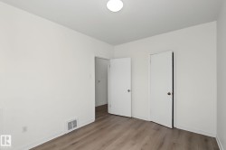 Room featuring wood-finish flooring, white walls, and a flush-mount ceiling light - 