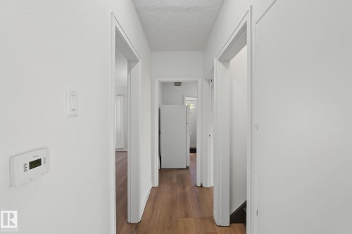 Hallway featuring wood-finish flooring, white walls, and multiple doorframes - 11147 78 Avenue Nw, Edmonton, AB 