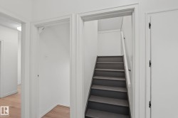 Staircase with gray treads and a white handrail, framed by white walls and doorways - 