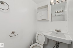 Compact bathroom featuring a wall-mounted sink, toilet, mirrored medicine cabinet, and wall-mounted storage cabinet - 