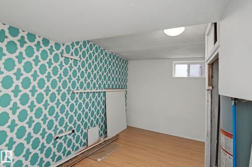 Room featuring a patterned accent wall and light wood-finish flooring - 11147 78 Avenue Nw, Edmonton, AB 