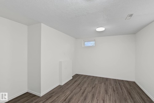 Interior room featuring wood-finish flooring, white painted walls, and a ceiling-mounted light fixture - 11147 78 Avenue Nw, Edmonton, AB 