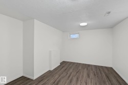 Interior room featuring wood-finish flooring, white painted walls, and a ceiling-mounted light fixture - 