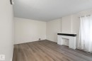 Spacious room featuring wood-finish flooring, a textured white fireplace with a dark mantel, and recessed lighting - 11147 78 Avenue Nw, Edmonton, AB  - Indoor Photo Showing Other Room 