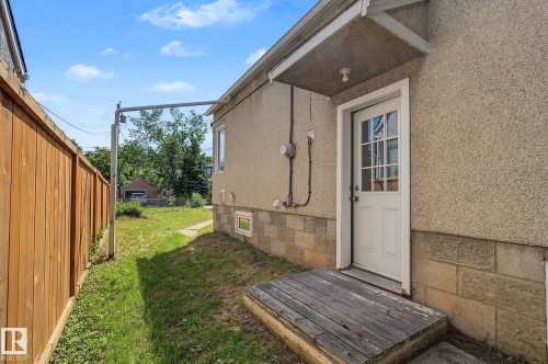 Stucco exterior featuring a white door with divided lites and an overhead awning - 11147 78 Avenue Nw, Edmonton, AB 