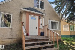 Front entry featuring a white paneled door with an arched glass insert, flanked by vertical wood-tone siding - 
