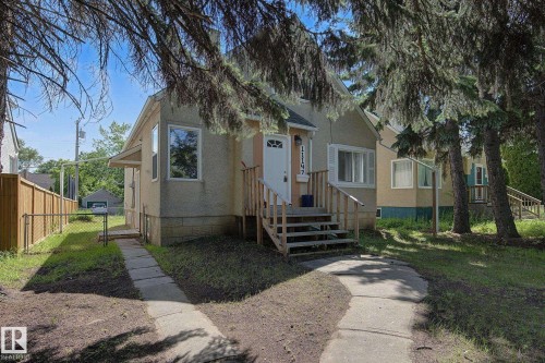 Stucco exterior residence featuring multiple windows and a front entrance with wood steps and railing - 11147 78 Avenue Nw, Edmonton, AB 