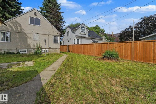 Expansive green space with a concrete pathway and a wood privacy fence - 11147 78 Avenue Nw, Edmonton, AB 
