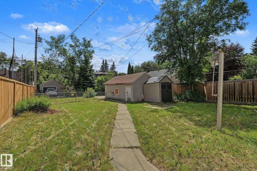 Expansive backyard featuring a concrete pathway, a detached single-car garage, and a garden shed - 11147 78 Avenue Nw, Edmonton, AB 