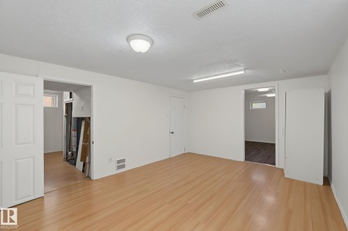 Spacious room with wood-finish flooring, white painted walls, and overhead lighting - 11147 78 Avenue Nw, Edmonton, AB 
