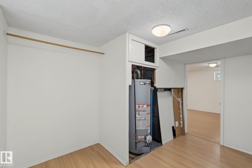 Utility area featuring a water heater, built-in storage, and wood-finish flooring - 11147 78 Avenue Nw, Edmonton, AB 